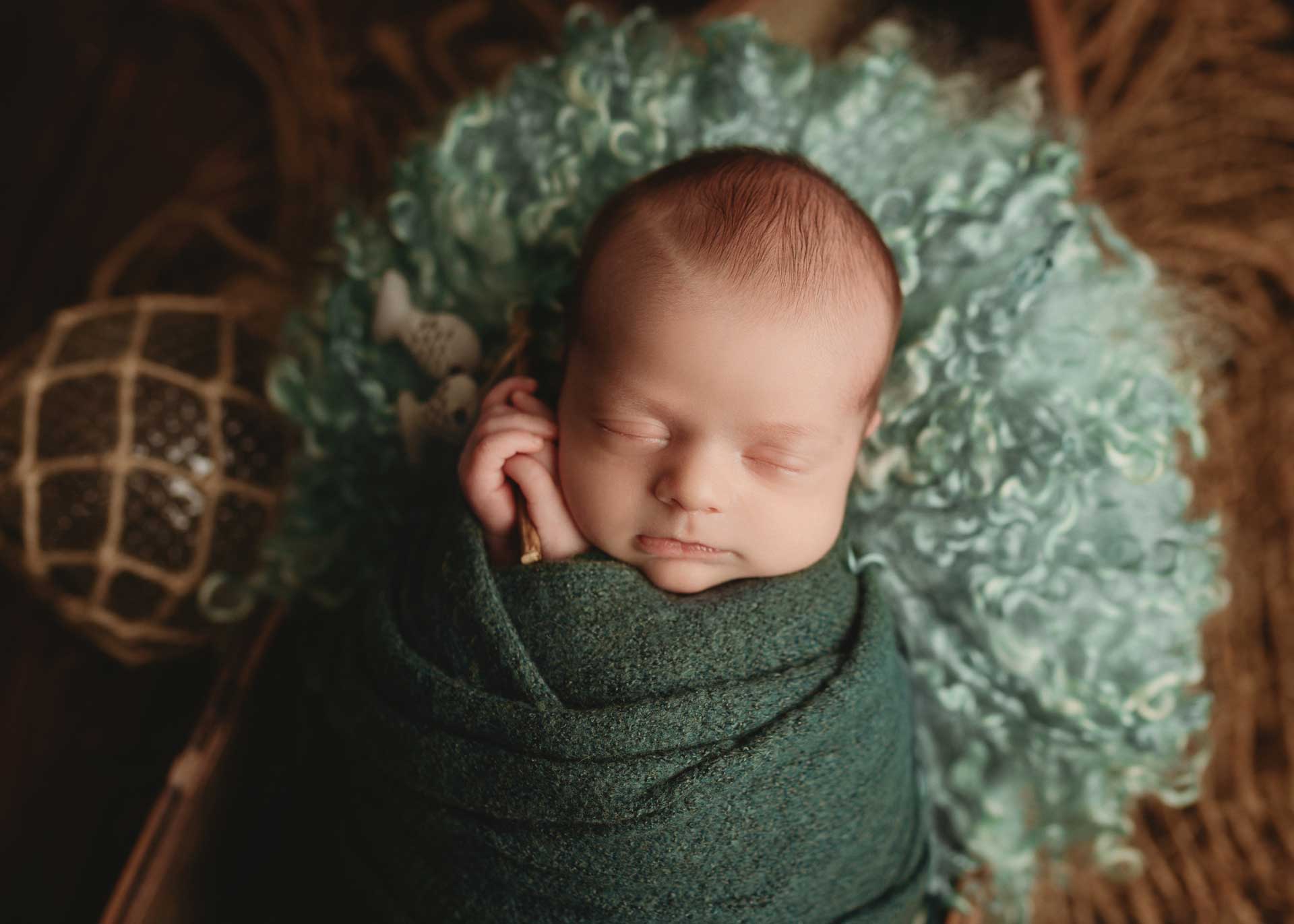 baby boy wrapped in sea green in boat prop with teal curly layer and fishing pole minneapolis mn newborn photographer