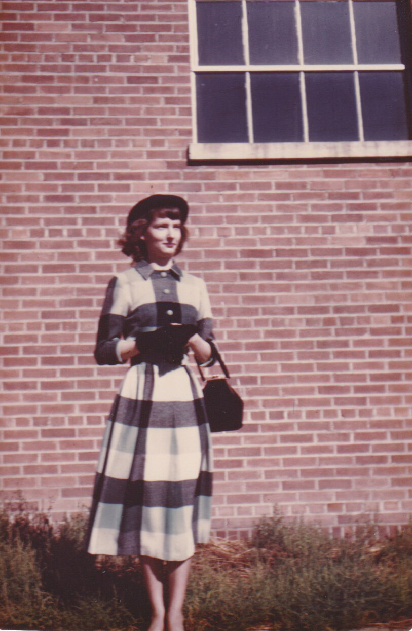 young woman in plaid dress, hats, and gloves in front of brick wall in the 1940s minneapolis family photographer