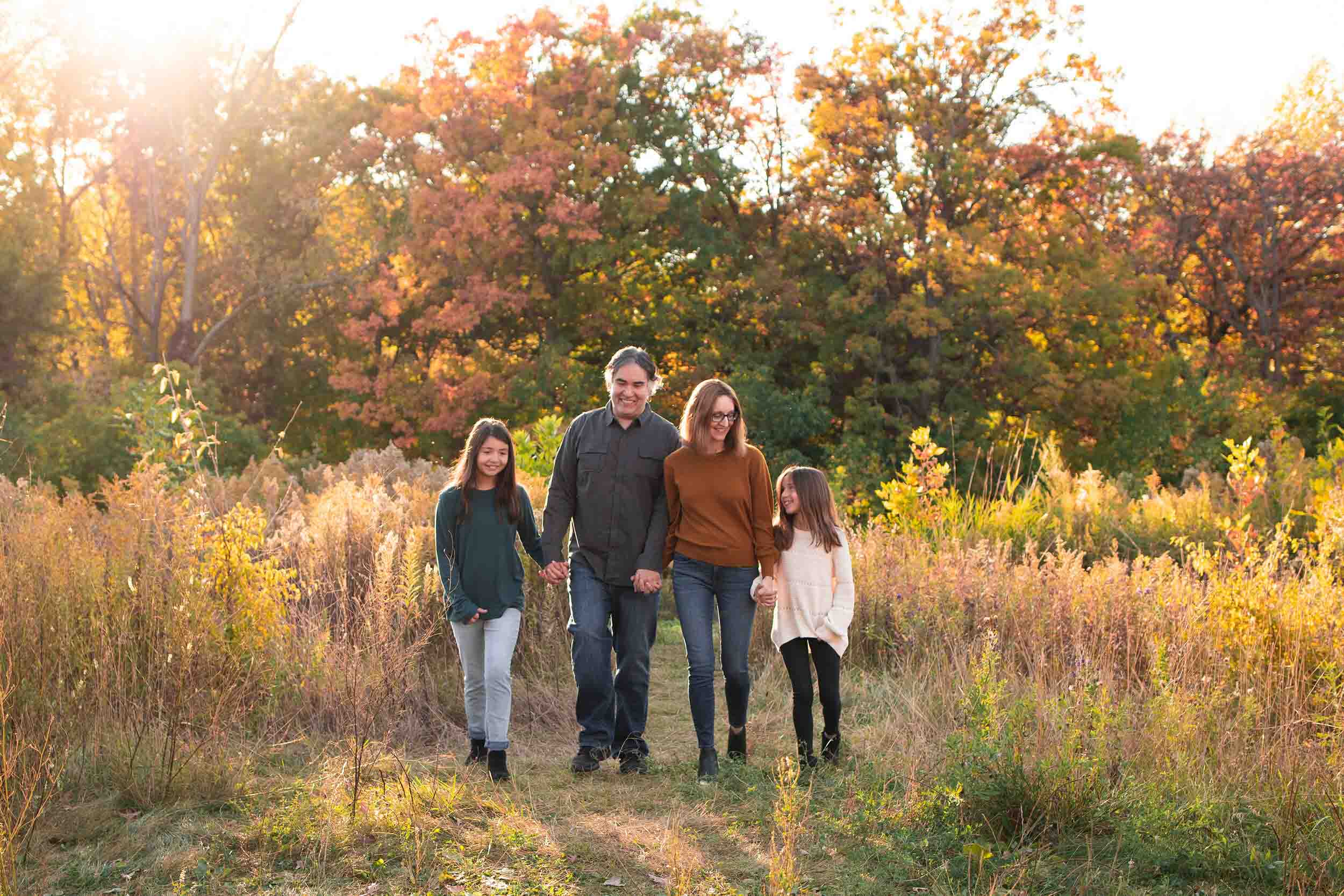 family walking hand in hand through field fall family photography session