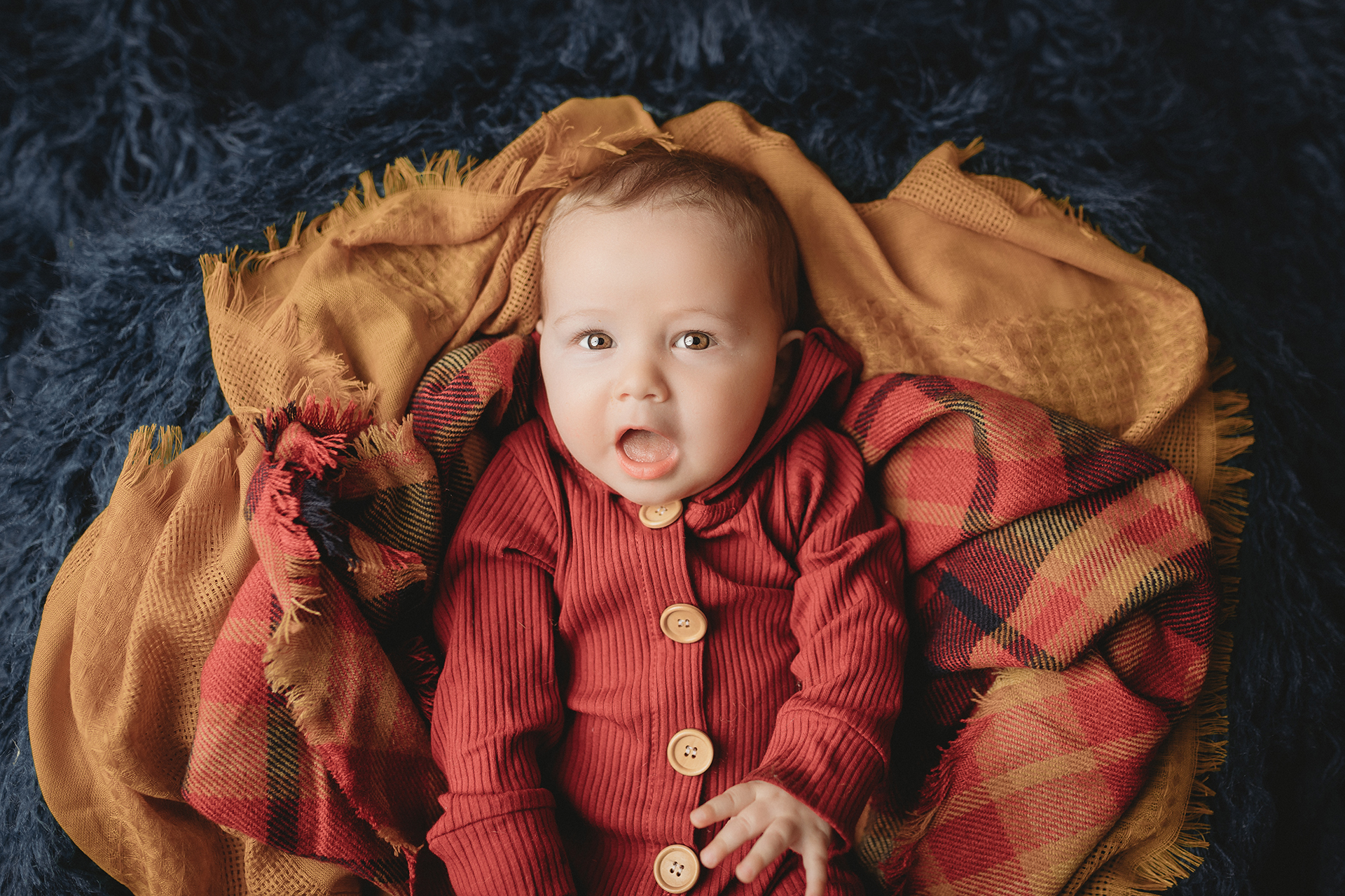 baby boy on fall colored plaid scarf and mustard layer for minneapolis newborn photography session