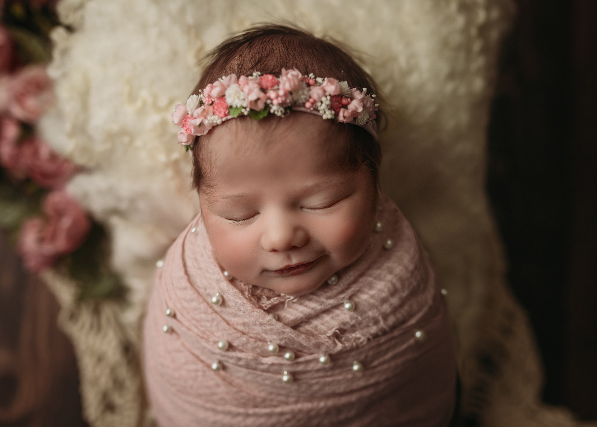 smiling newborn girl in pink pearls and flowers for newborn photography in minneapolis