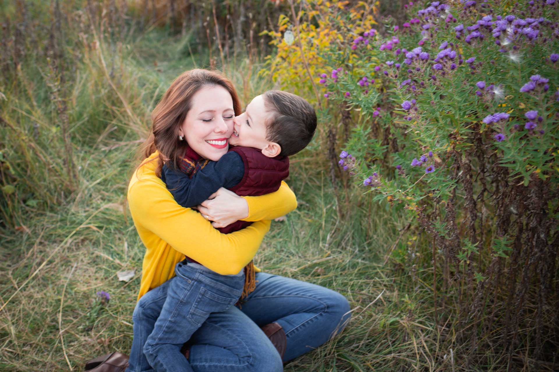 mom in yellow sweater hugging toddler son in field minneapolis family photographer