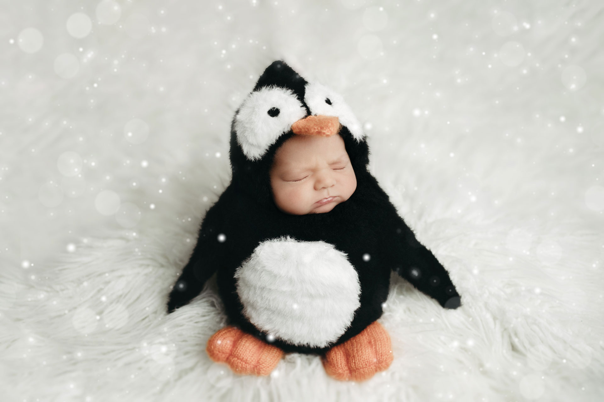 baby girl in penguin sack potato pose on white float
